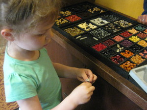 Fancy Free Daughter making a pay-by-the-inch beaded necklace at Kidani's Community Hall